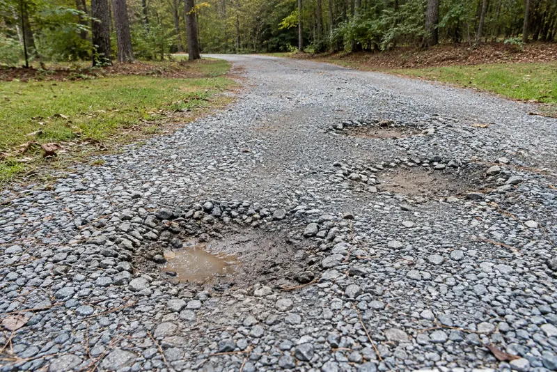 Rounded potholes in a gray gravel driveway