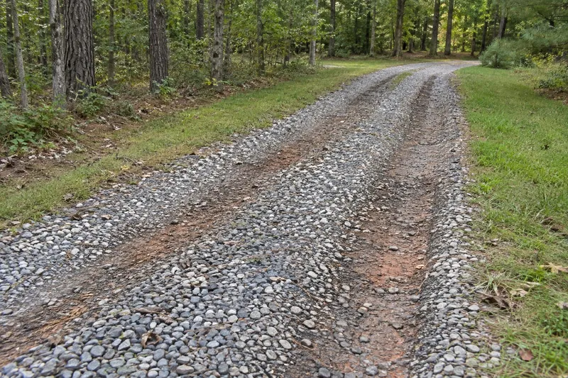 Two depressed wheel tracks along a gravel driveway