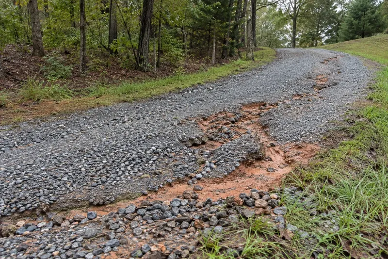 Runoff erosion channels in a sloping gravel driveway