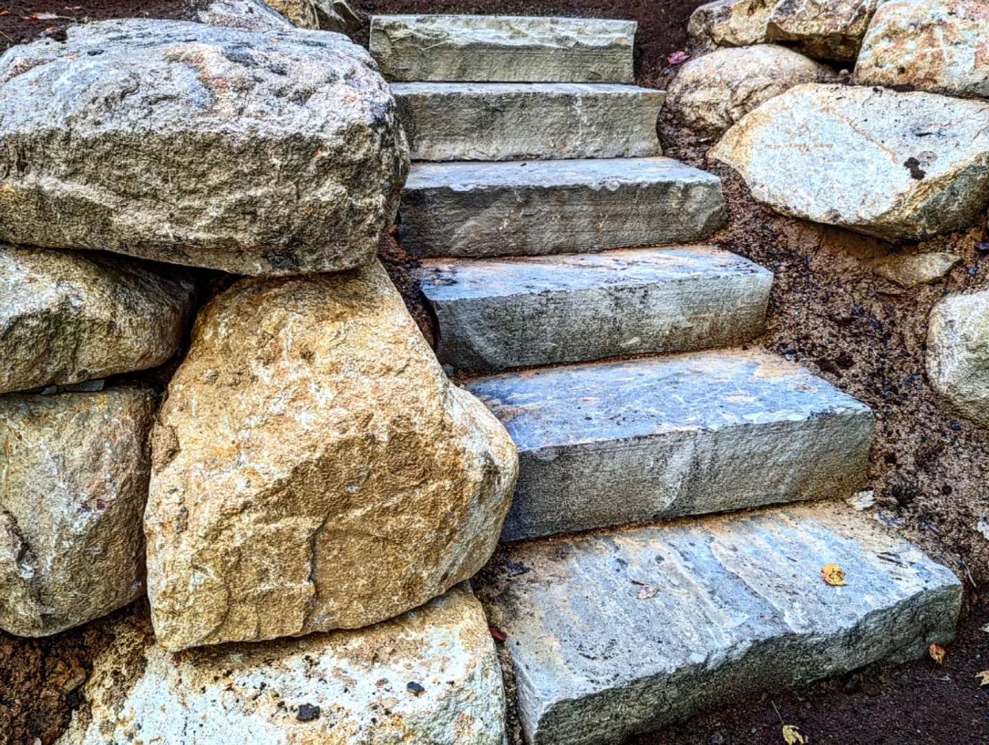 Stone steps with boulders creating a natural stairway through a landscaped hillside