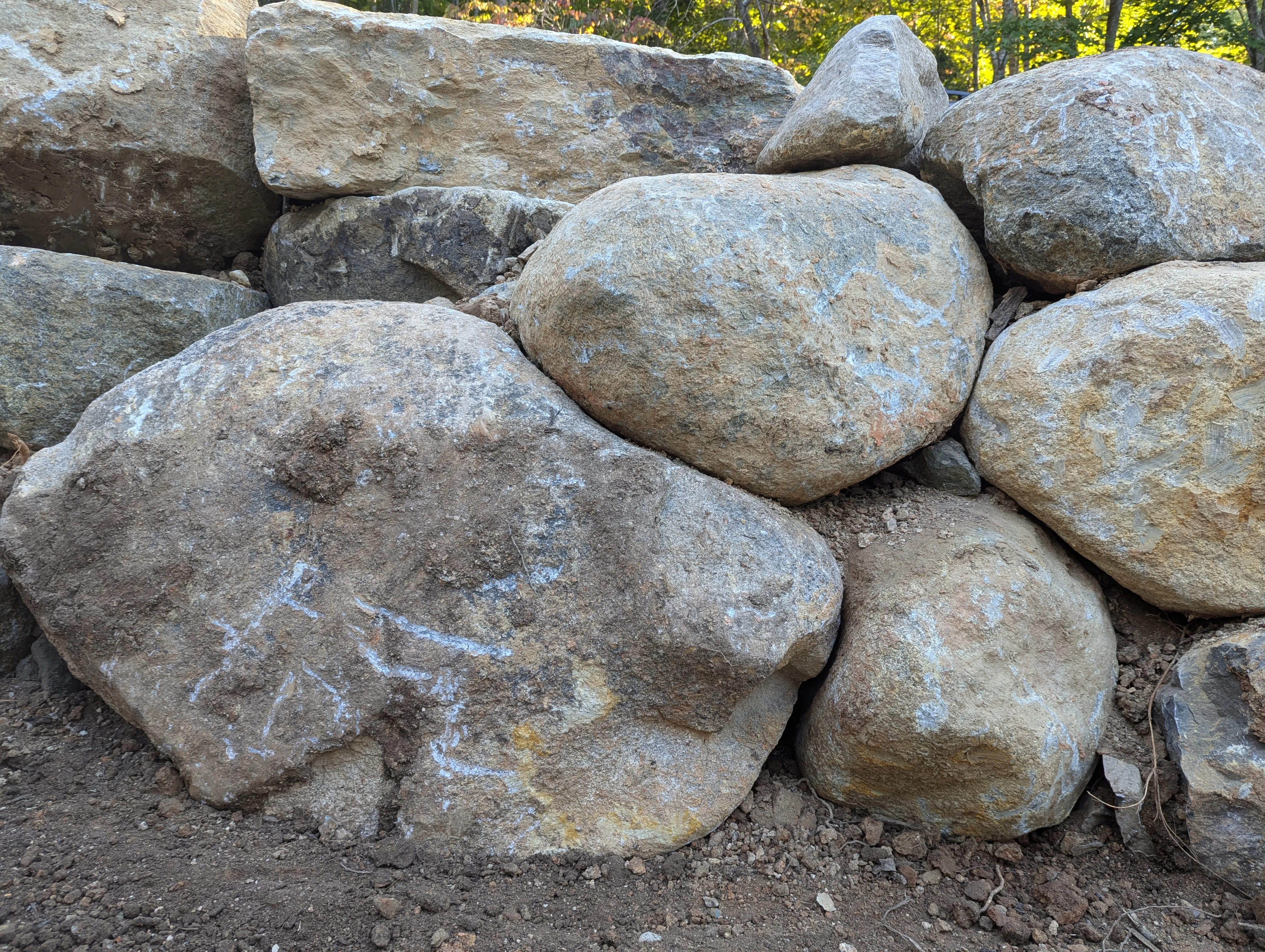 Large boulder retaining wall holding back a sloped yard