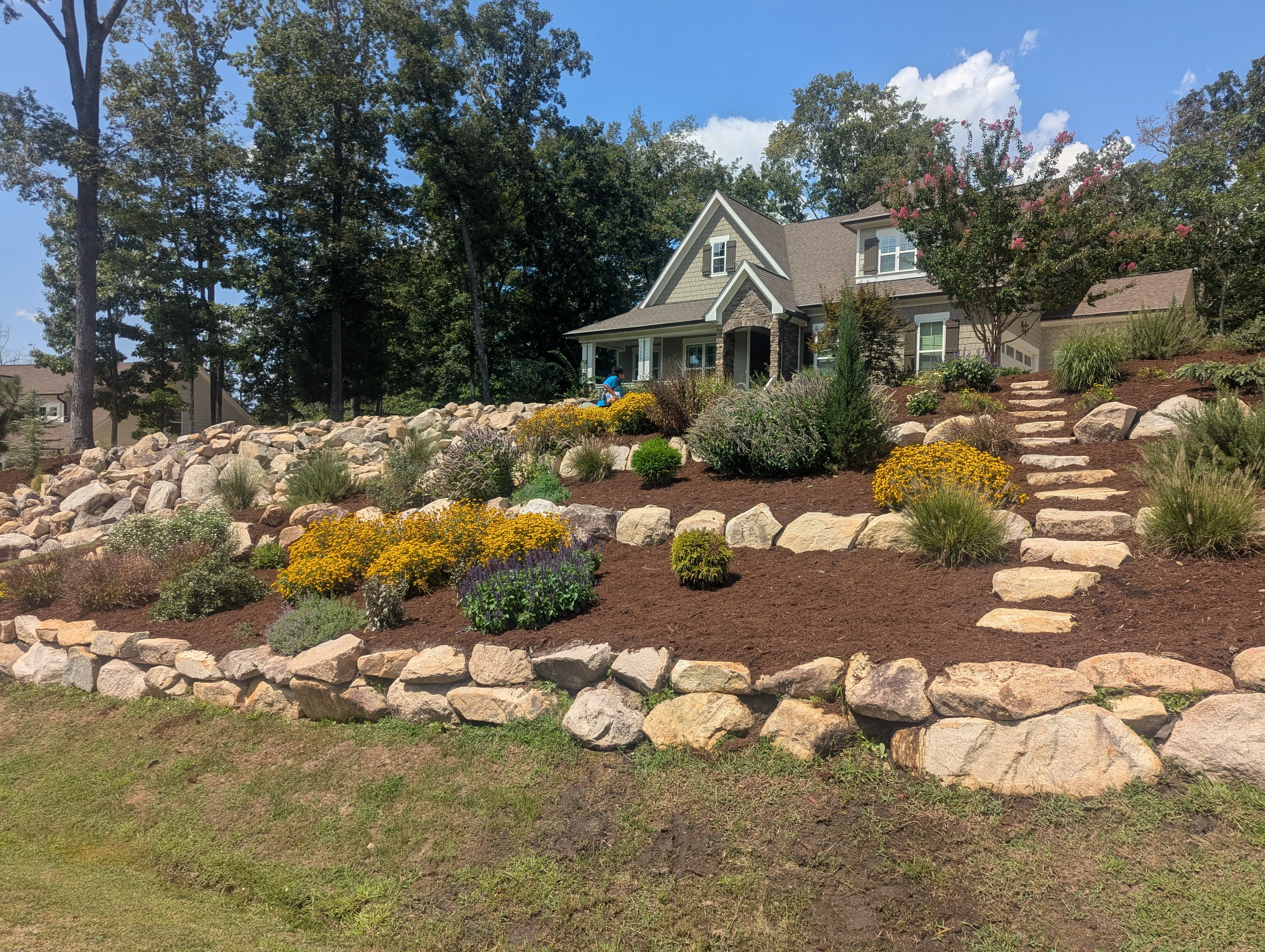 Boulder retaining wall installed along the foundation of a residential home