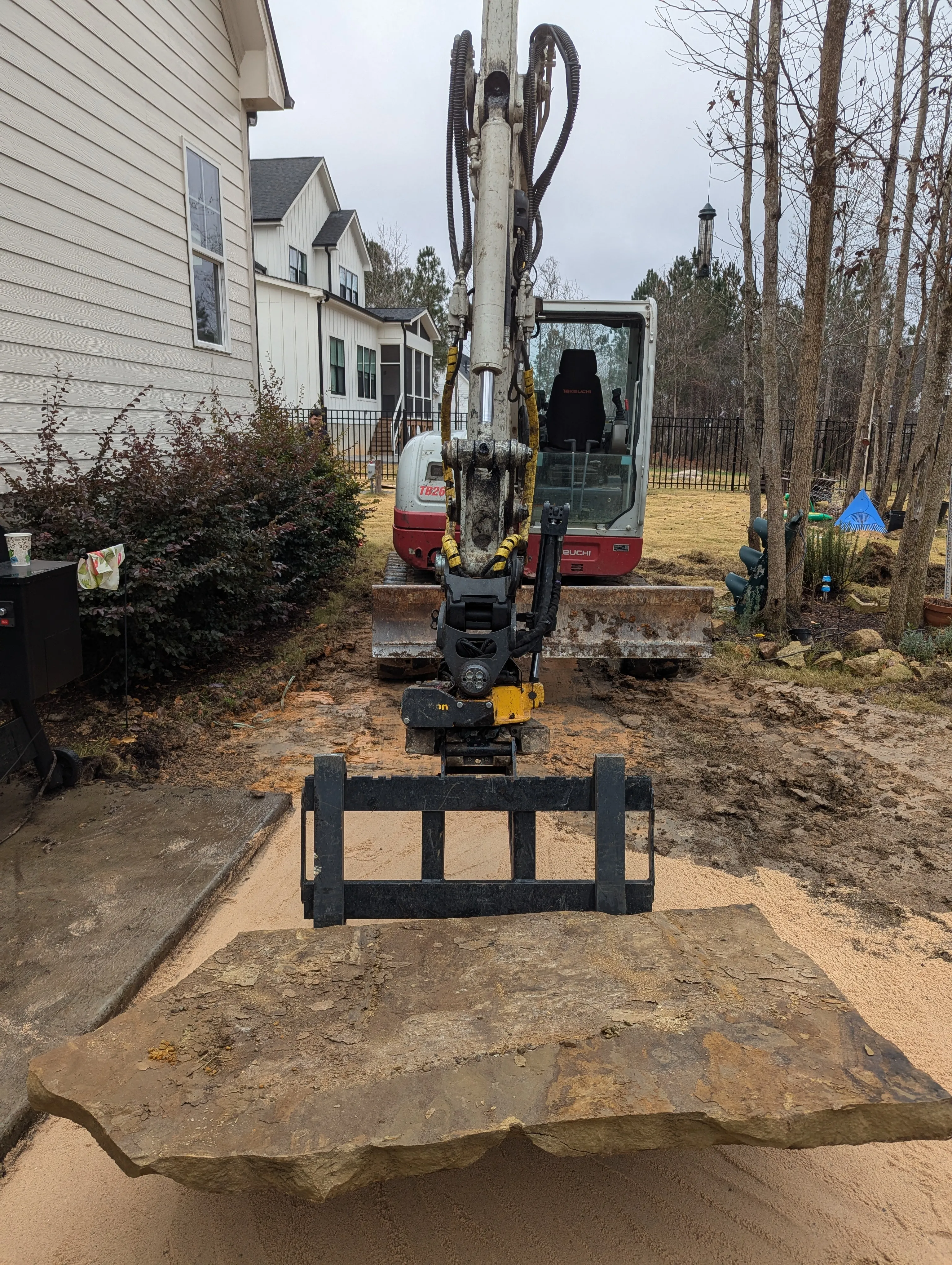 Crew using equipment to move a large flagstone slab into position during installation